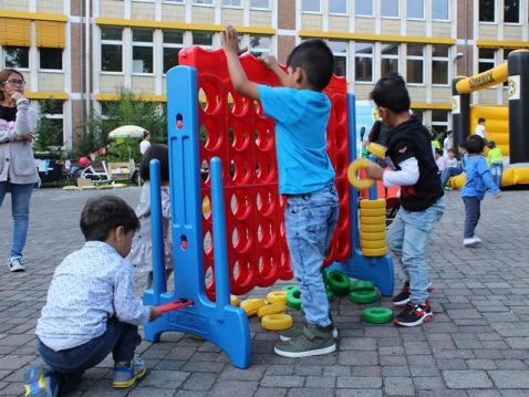 Kinder spielen an einem grossen bunten Spielzeug auf einem Hof